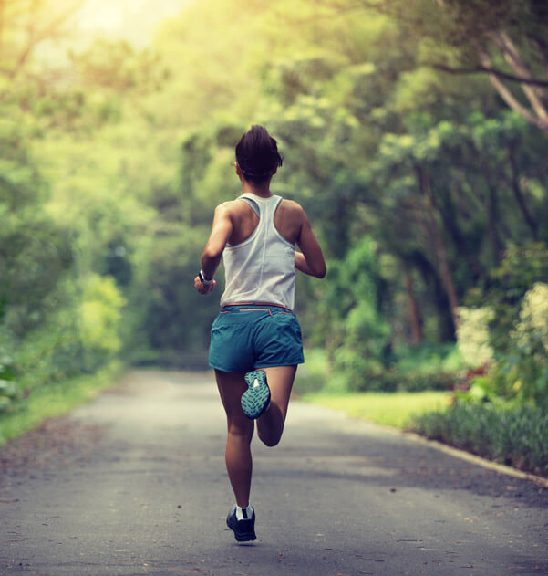 Female runner running at summer park trail . Healthy fitness woman jogging outdoors.