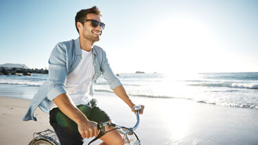 Cropped shot of a young man cycling on the beach.