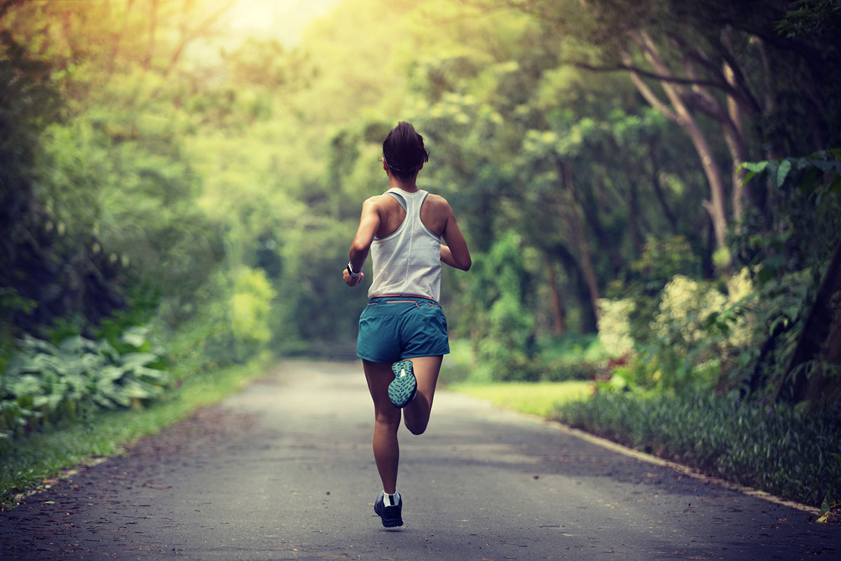 Female runner running at summer park trail . Healthy fitness woman jogging outdoors.