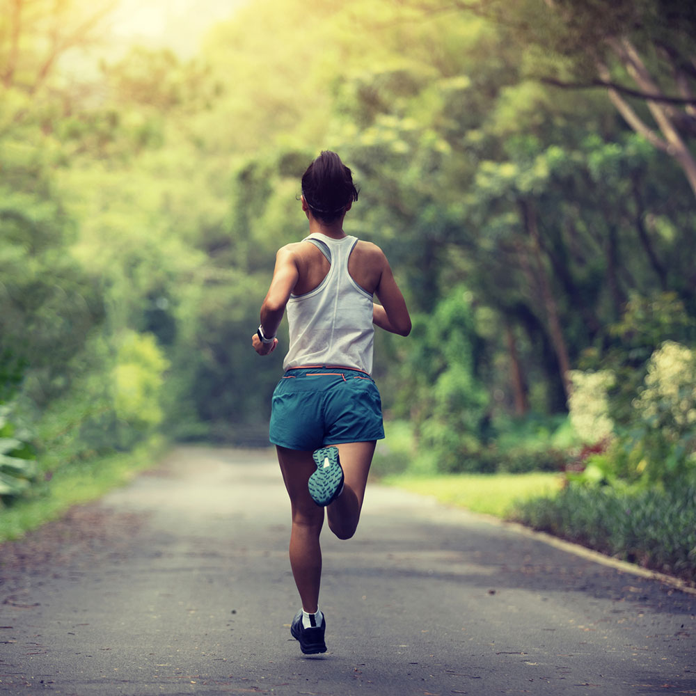 Female runner running at summer park trail . Healthy fitness woman jogging outdoors.