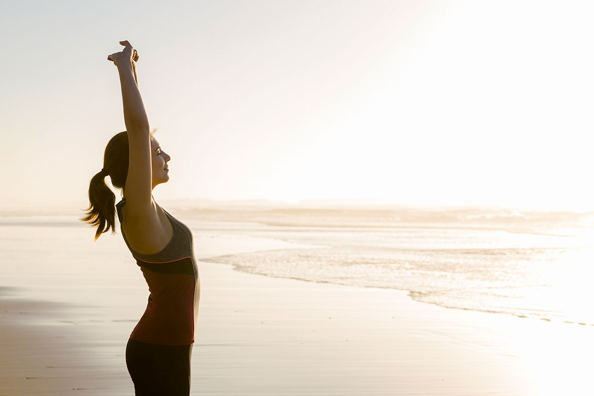 Shoot of a beautiful woman making stretching exercises in the beach.