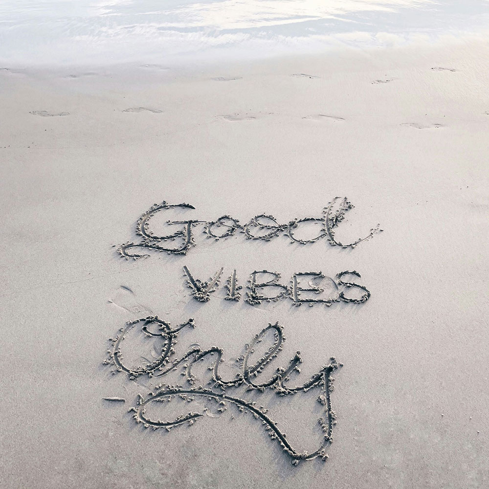 "Good Vibes Only" written in sand on the beach