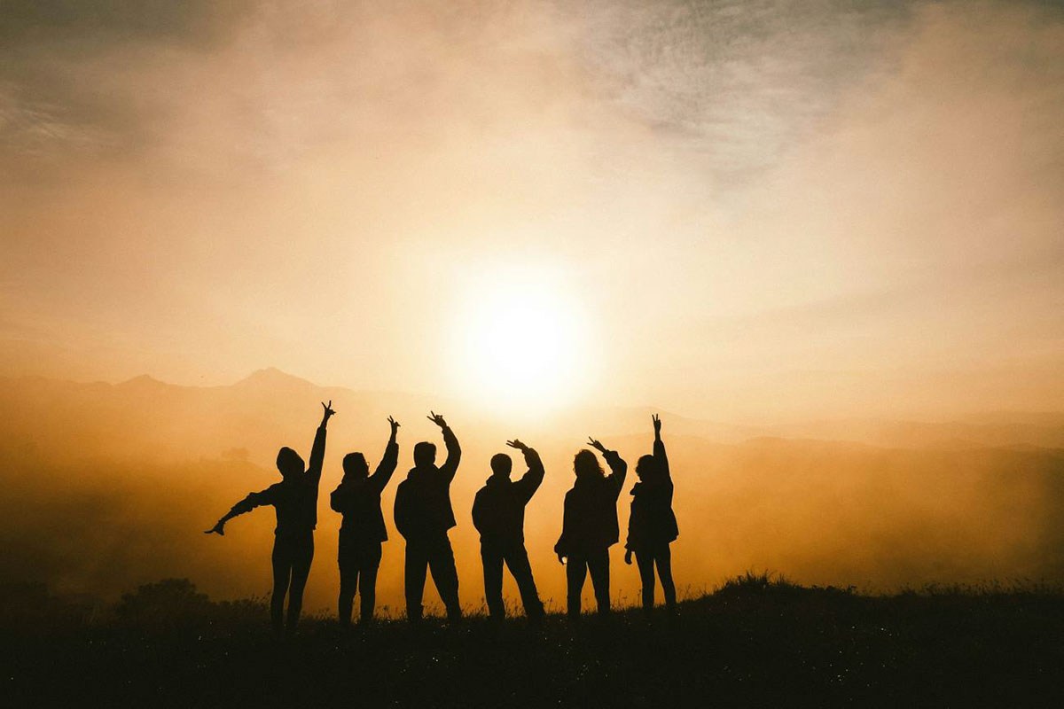 group of people posing in front of a sunset