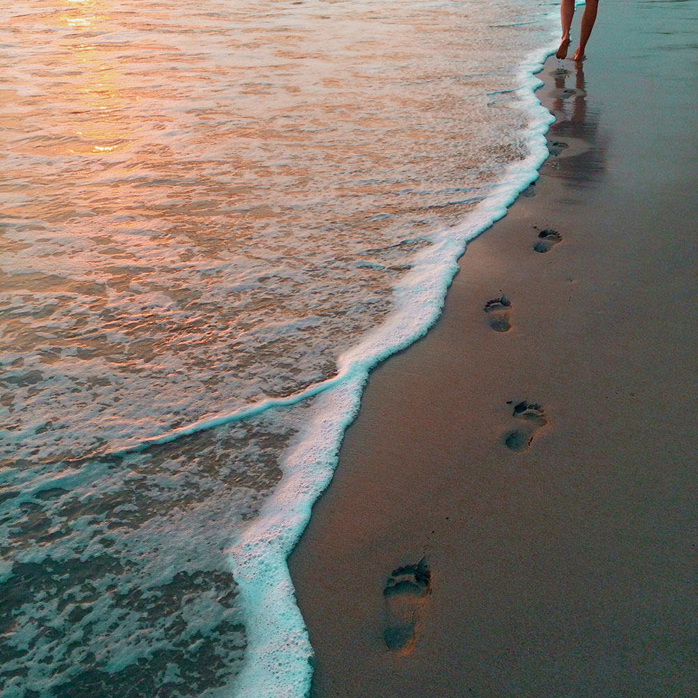 person walking on the beach at sunset